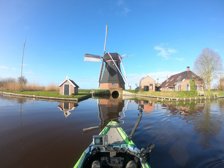 view from the kayak of a small farm with a windmill 