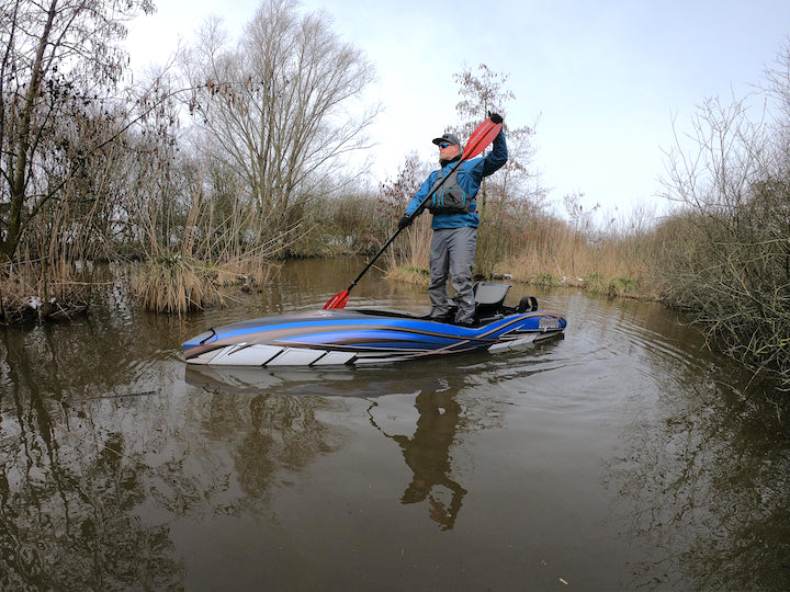 Dennis stands in his fishing kayak on a small river