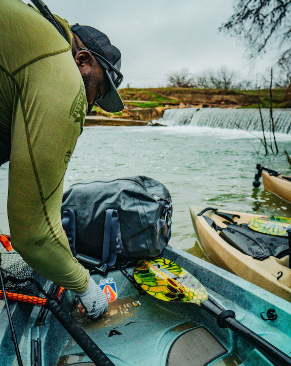 man prepping his kayak to take out fishing on the river