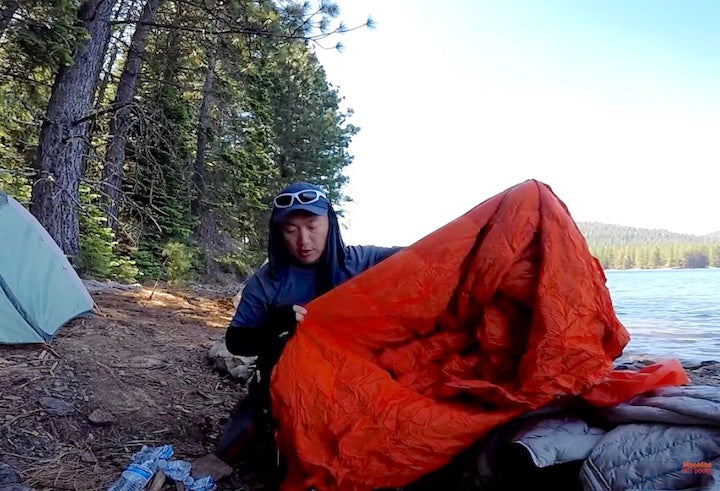 Moo Lee with light down blanket at kayak campsite