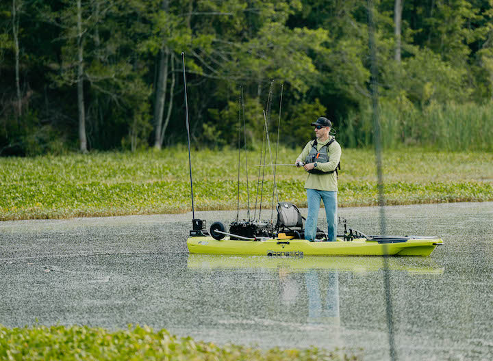 man standing in fishing kayak, fishing
