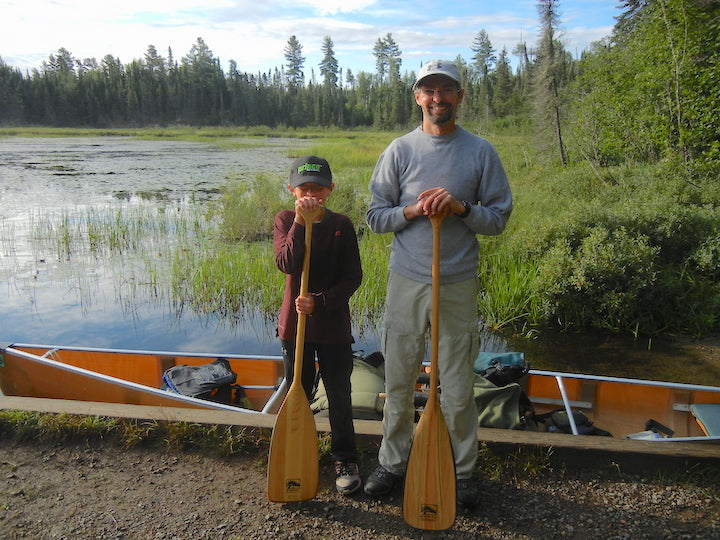 dad and young son next to loaded canoe, ready for a trip