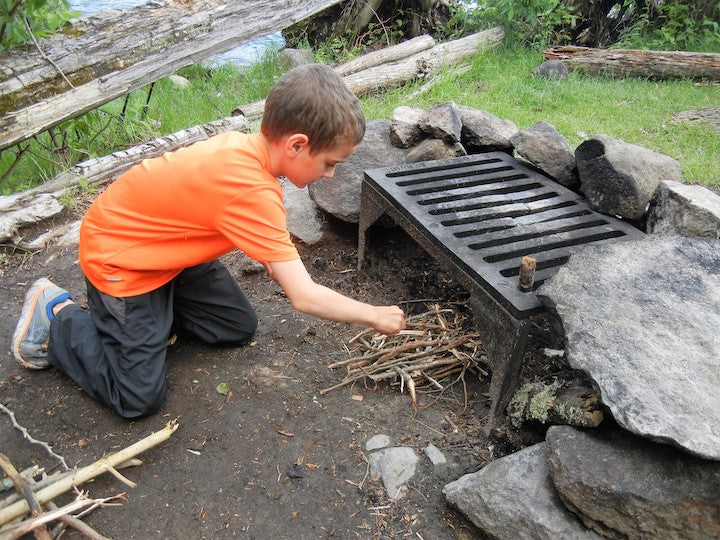 young boy starting a campfire