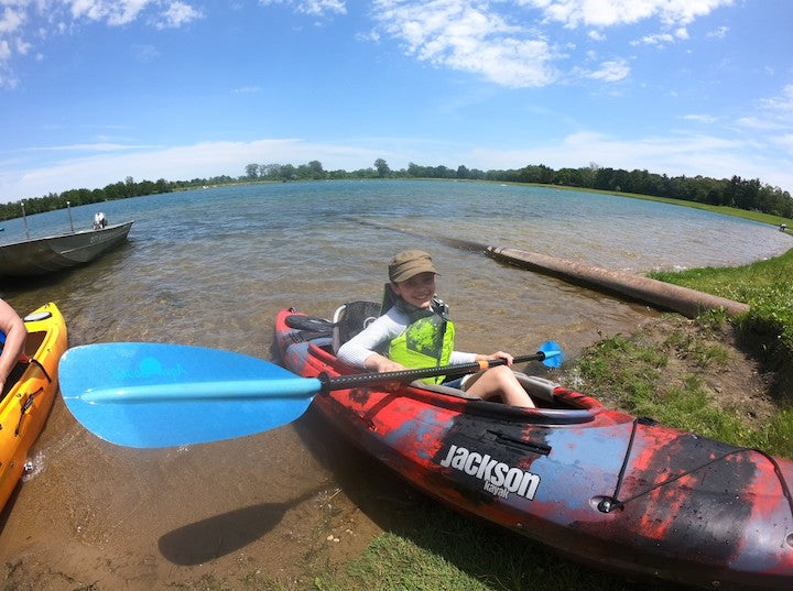 youth in a kayak on the beach, ready to paddle