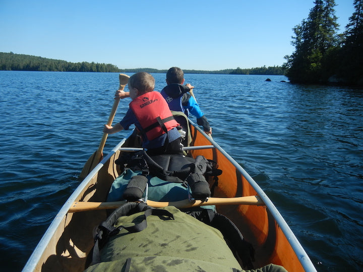 two young boys in the front of a canoe on a canoe trip