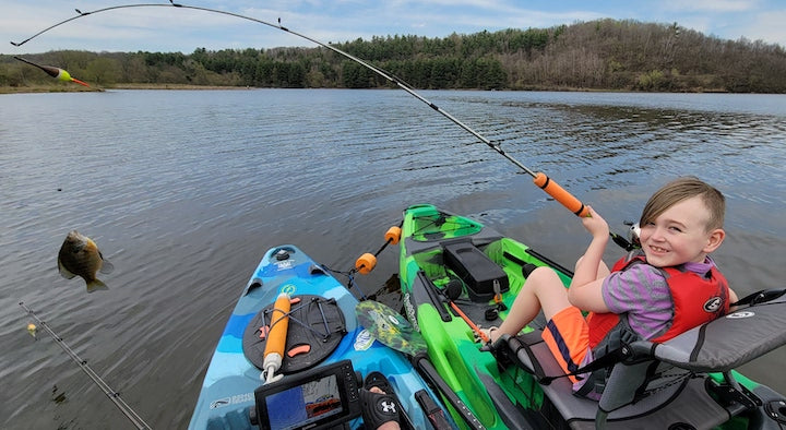 jackson thiede has a bluegill on his line, sitting in his fishing kayak