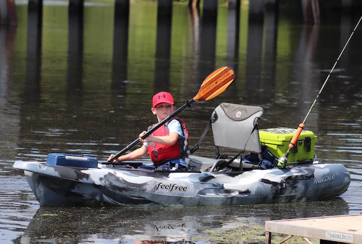 a young boy paddles his fishing kayak