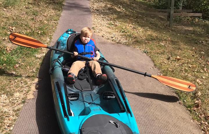 little guy in a big kayak with Bending Branches Navigator kayak paddle (on the ground)