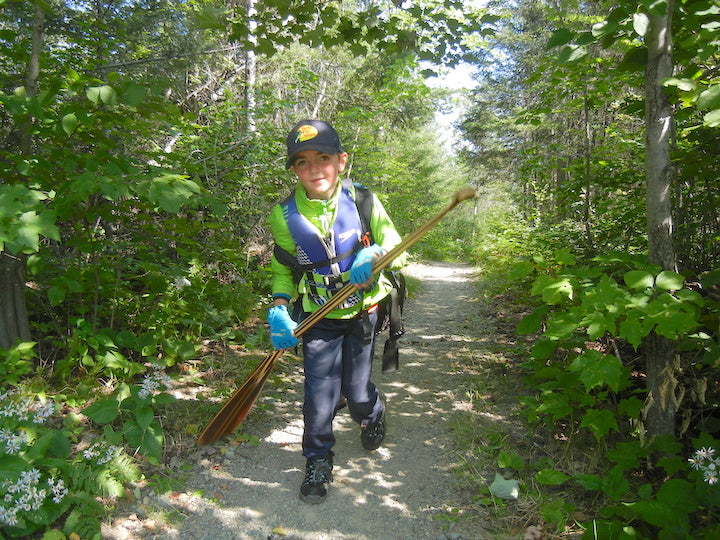 rohan strege on a canoe trip portage, carrying gear