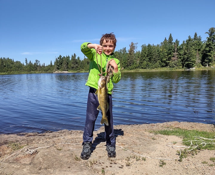 young boy with big fish on the lakeshore