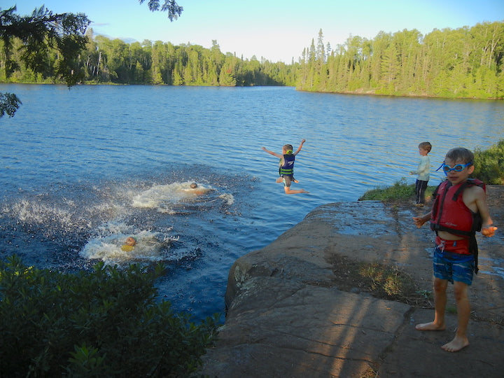 a bunch of boys swimming at a boundary waters campsite