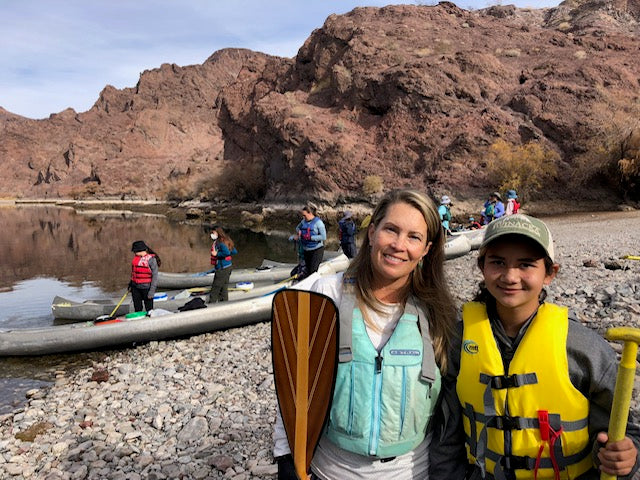 Kristen Elgo with a teen girl, standing in front of other girls and canoes along the Black Canyon shore