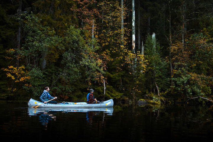 two people in a tandem canoe on a lake in autumn