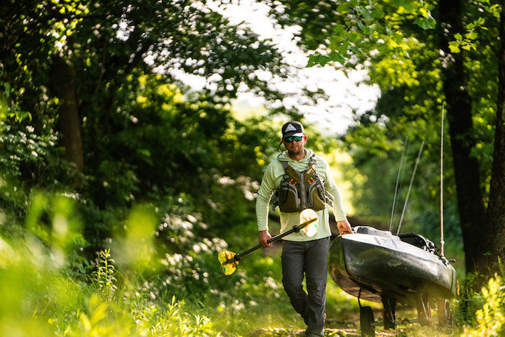 kayak angler carts his fishing kayak to the river