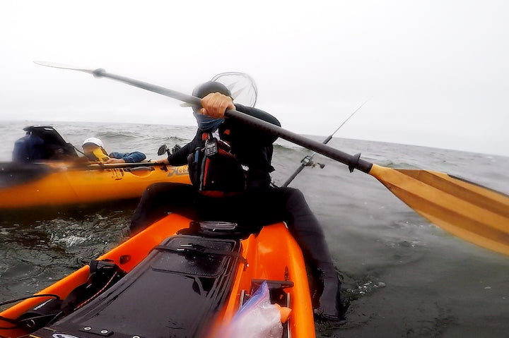 kayaker helps another kayaker reenter his kayak in the ocean