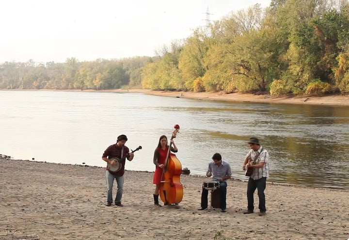 Okee Dokee Bros playing with a drummer and bassist next to the Mississippi River