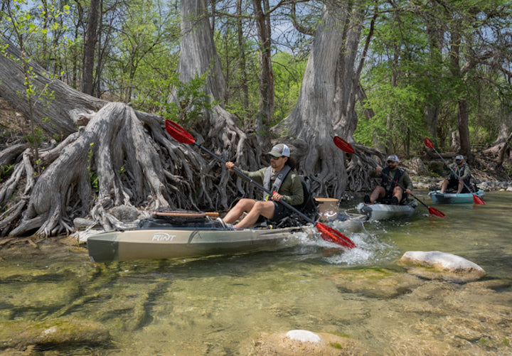 three men in fishing kayaks on a clear Texas river
