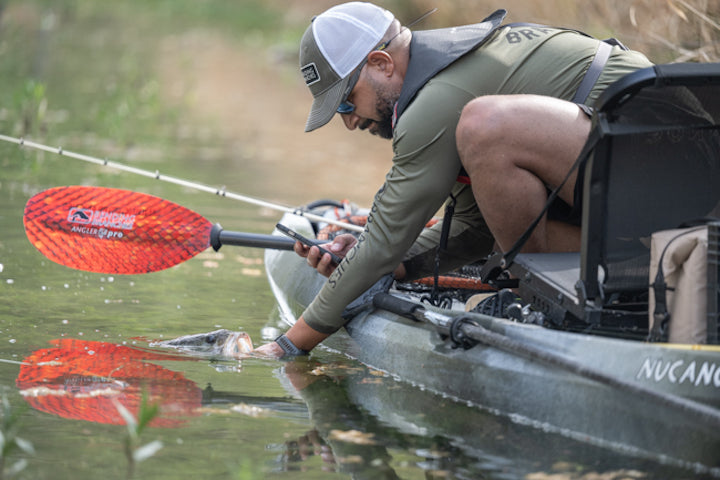 Terrell Hester in his kayak with a fish at water's edge