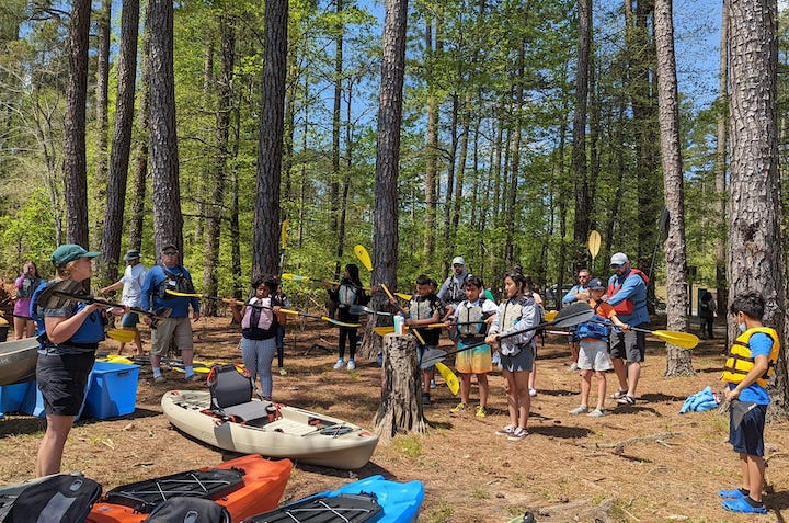 adult shows kids about kayak skills on shore