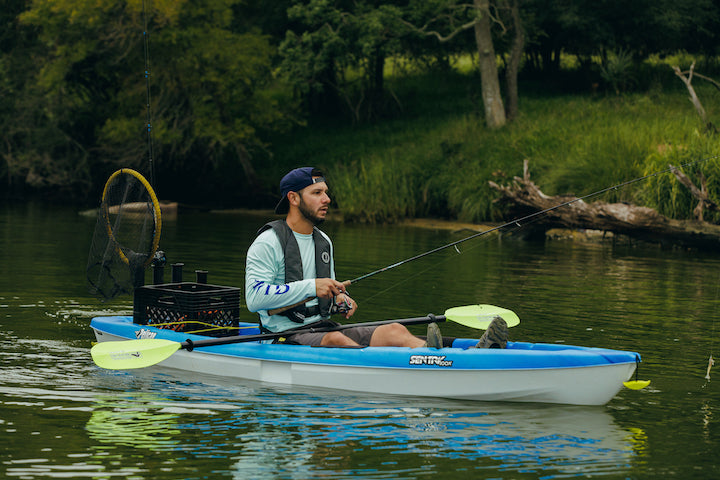 man wearing an inflatable PFD fishes out of a kayak