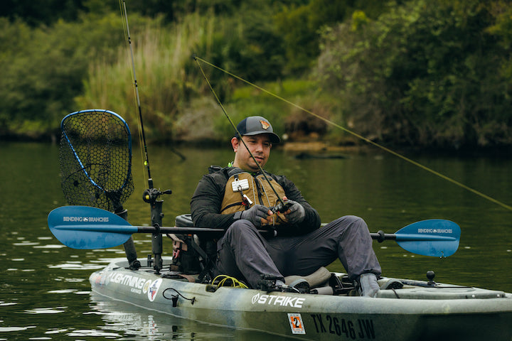 man wearing a traditional PFD fishes out of a kayak
