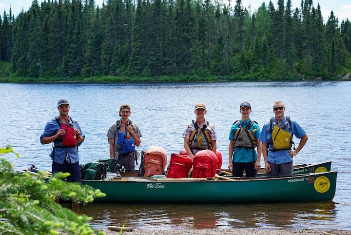 five teen boys with their loaded canoes