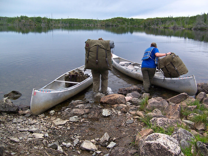 two women load canoe packs into their canoes