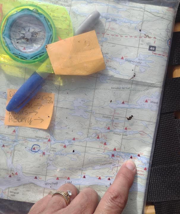 finger points to a campsite on a Boundary Waters map, with compass