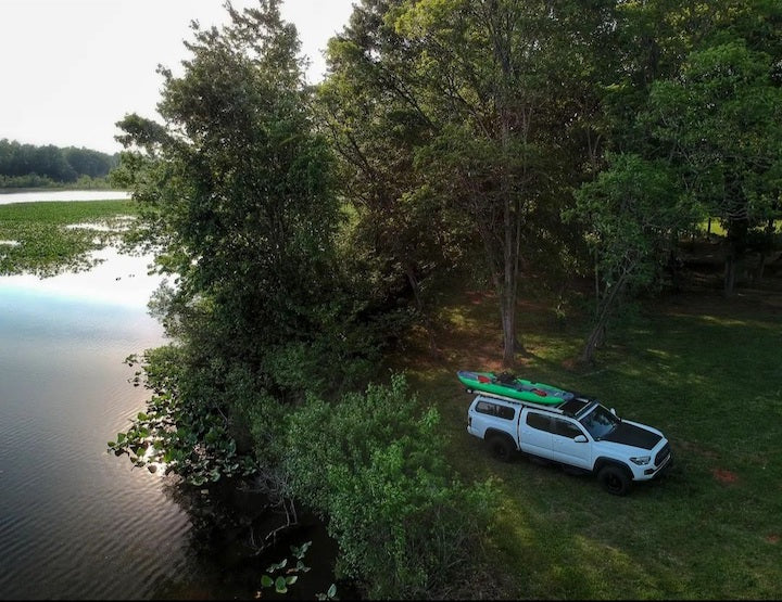 drone shot of a truck and fishing kayak next to a river