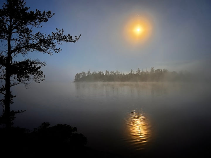 sun rising in the mist over a wilderness lake
