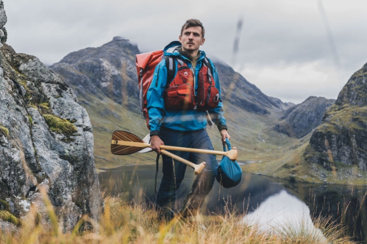 man portaging in Scotland with packs and Bending Branches paddles