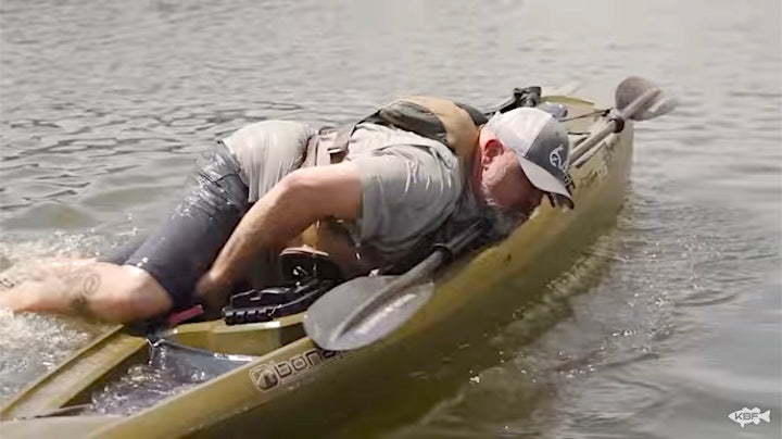 man hoisting himself on top of kayak on his belly