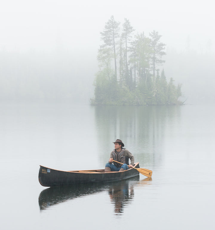 solo canoeist on a still, misty lake