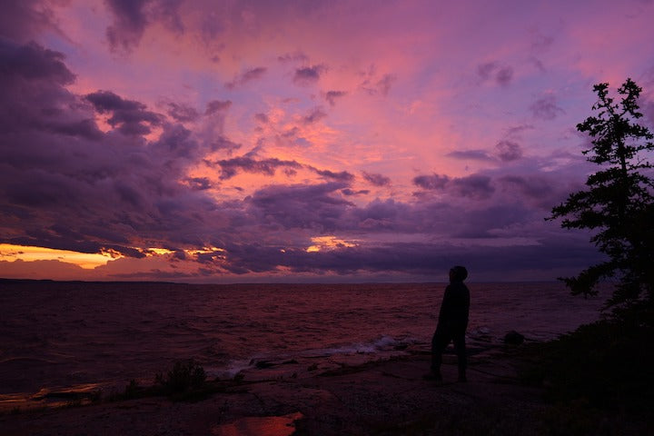 the sun starts to peak, purple and yellow clouds along Superior's shoreline