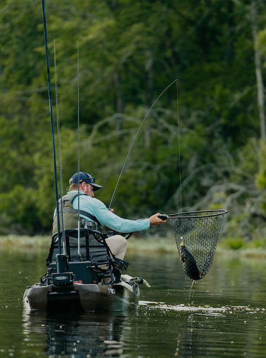 man has a fish in his net, kayak fishing