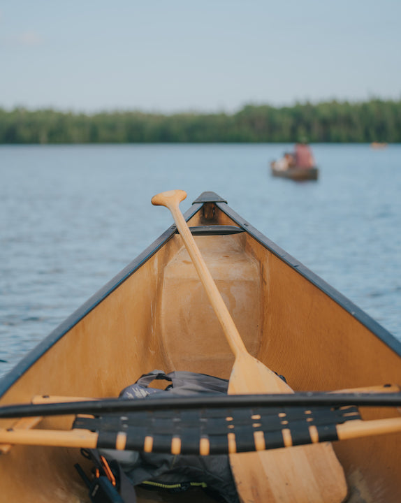 bow of canoe in the water with Bending Branches paddle, another canoe in front