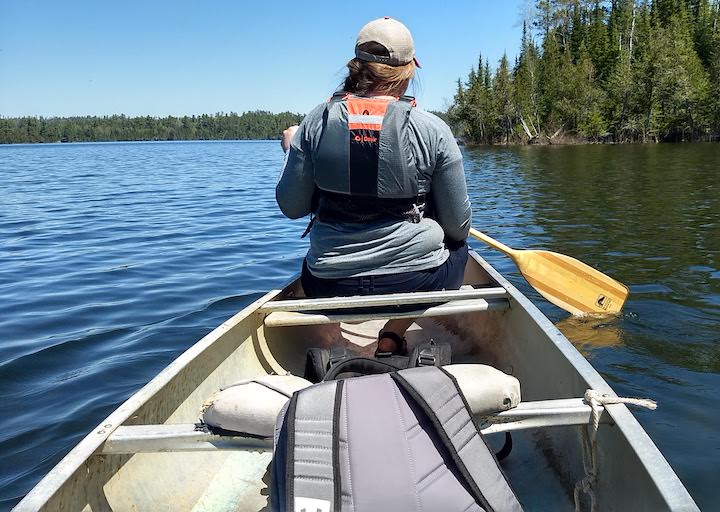 woman in canoe bow paddling on a lake