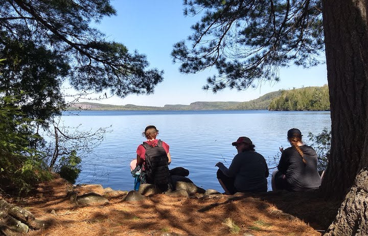 three women sitting lakeside with lunch