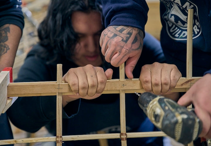 Young men work together to frame a canoe with Urban Boatbuilders