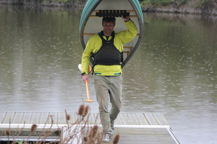 Pete Scutt portages a canoe from their dock on the River Thames