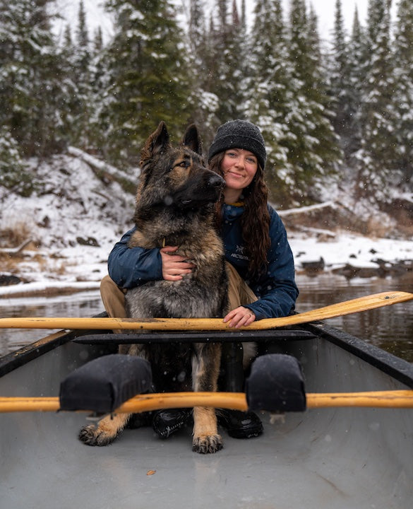 Ashley Bredemus and her dog sitting in her canoe on a Minnesota lake in early winter