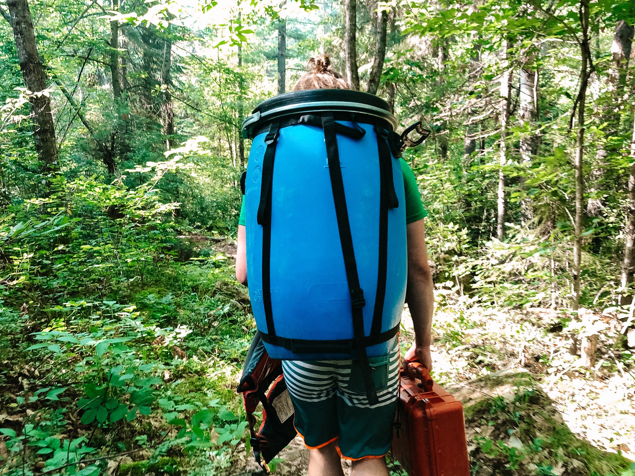 Man carrying a barrel on his back through the portage trail