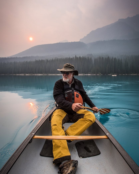 older man in a canoe on a blue mountain lake