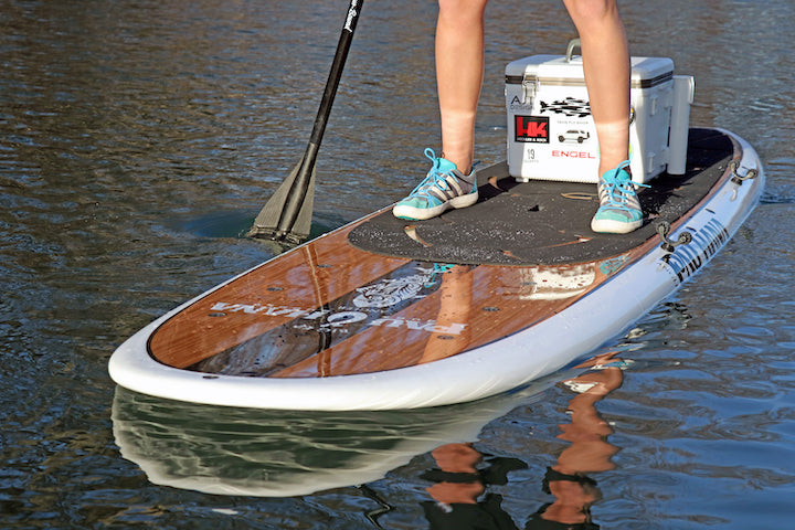 paddleboard with paddler's legs, paddle on the water, showing his wide stance