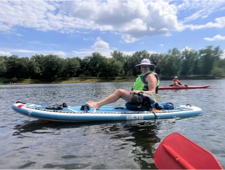 woman paddles a hybrid SUP/kayak with footrest