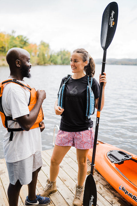 woman and man standing on a dock next to a kayak, woman holding a Sting Ray Carbon paddle