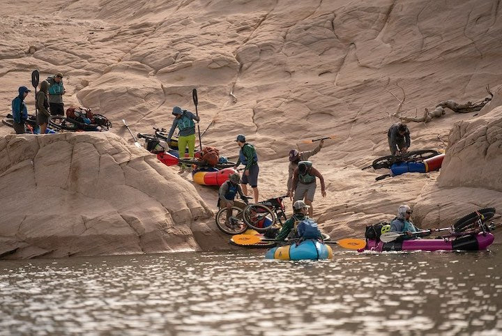 a group of bikerafters in a canyon, along the shore getting ready for the river