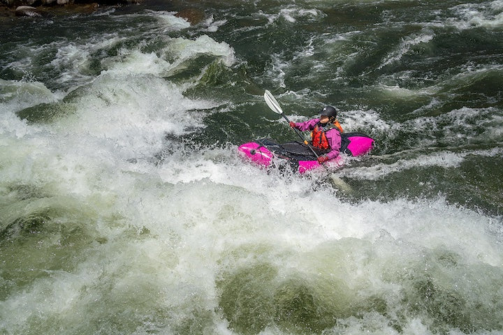 packrafter in pink packraft going through tough rapids