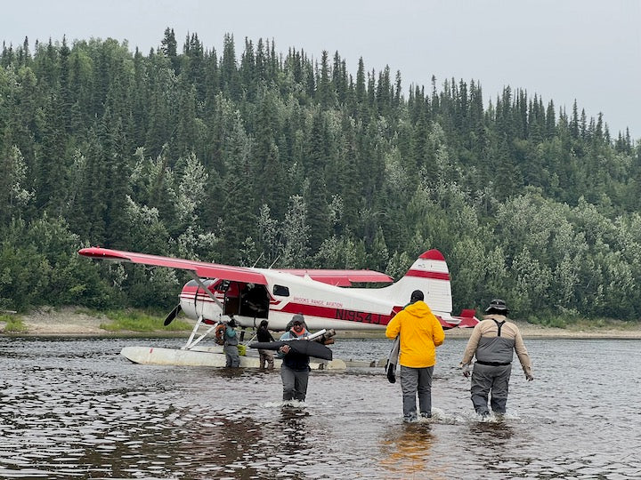 men going back and forth through shallow water to a small float plane