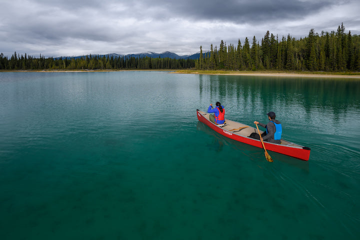 two people in a red canoe on a mountain lake